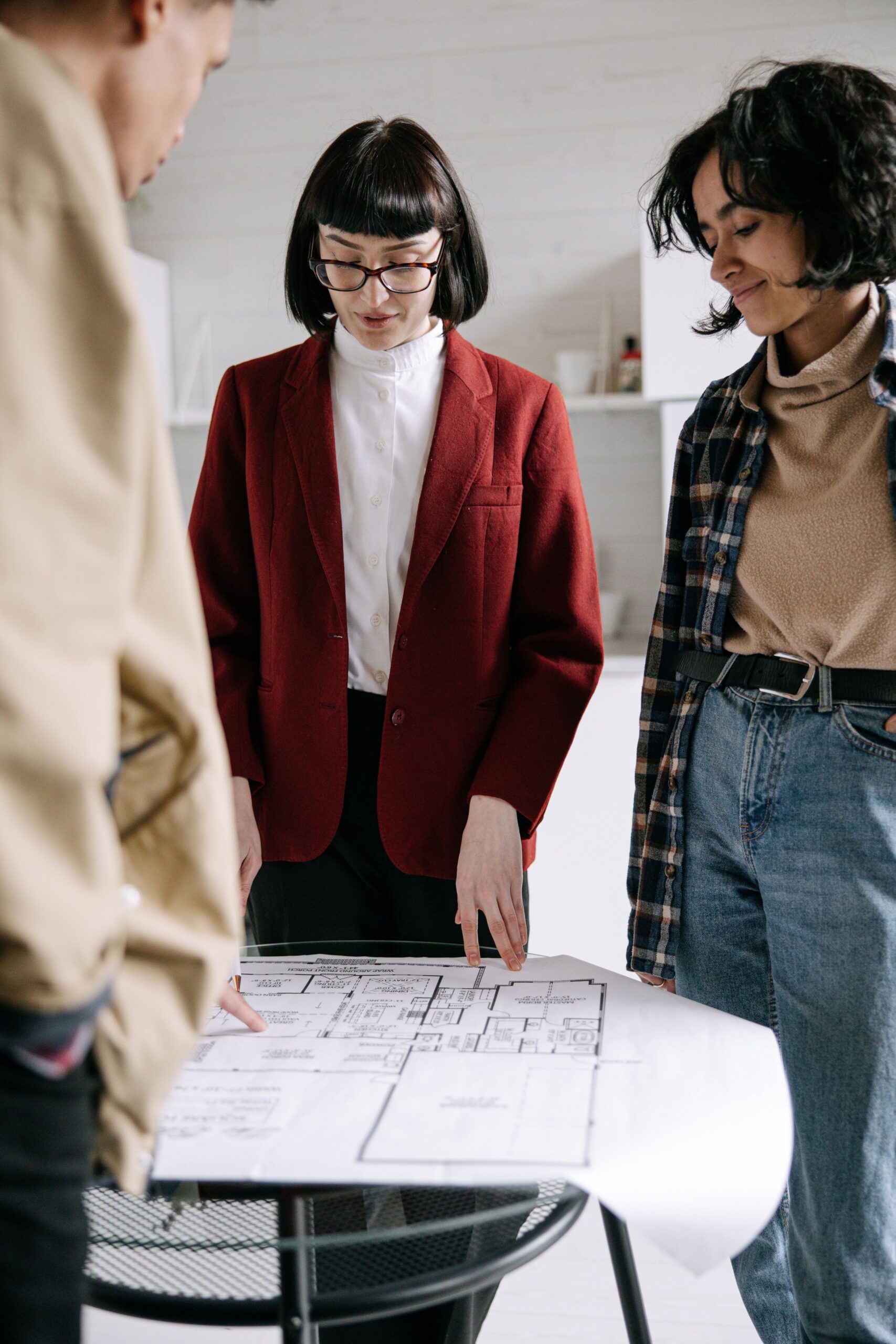 Real estate agent explains floor plans to clients during a property tour indoors.